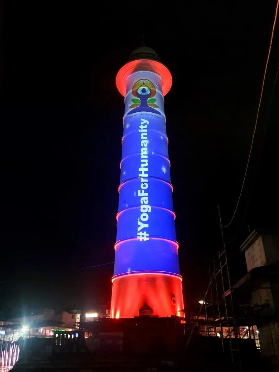 The tower in blue with a red base, the yoga emblem near the top and the hashtag YogaForHumanity down the shaft.